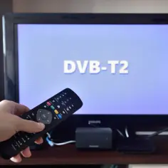 Pilot do telewizora w ręce, ekran pokazuje "DVB-T2". Odkryj darmowe kanały tv naziemnej i ciesz się ulubionymi programami.