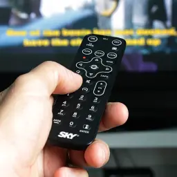 Dłoń trzyma pilot Sky, próbując rozwiązać problem, gdy telewizor nie wyszukuje kanałów naziemnych.