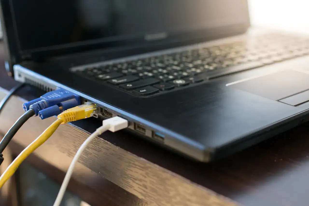 Kabel VGA i sieciowy podłączone do laptopa. Dowiedz się, jak podłączyć drugi monitor, aby zwiększyć produktywność.