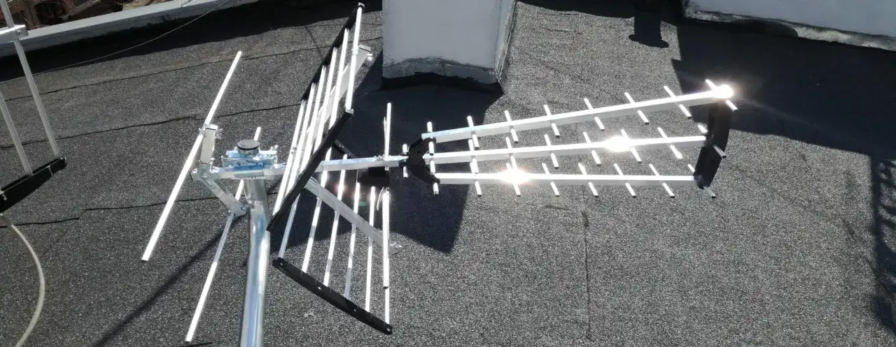 Srebrna antena telewizyjna zamontowana na dachu, gotowa do odbioru sygnału. Idealna antena na balkon dla lepszego zasięgu.