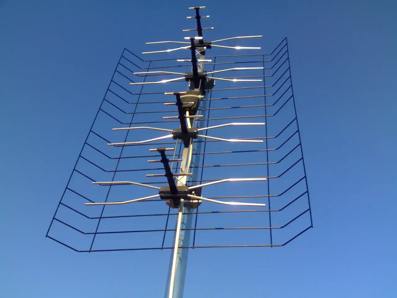 Antena kierunkowa DVB-T z elementami odbiorczymi skierowana ku błękitnemu niebu.