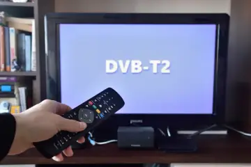Pilot do telewizora w ręce, ekran pokazuje "DVB-T2". Odkryj darmowe kanały tv naziemnej i ciesz się ulubionymi programami.